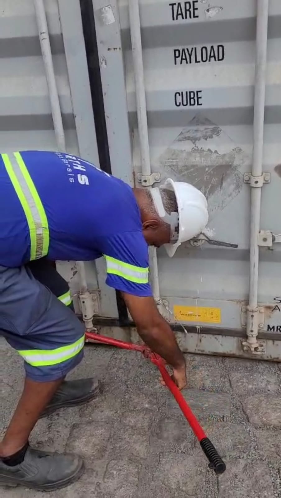 Colaborador abrindo as portas de um contêiner com barra de apoio